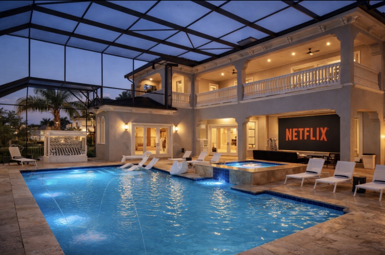 Covered outdoor pool, spa, and movie screen at dusk